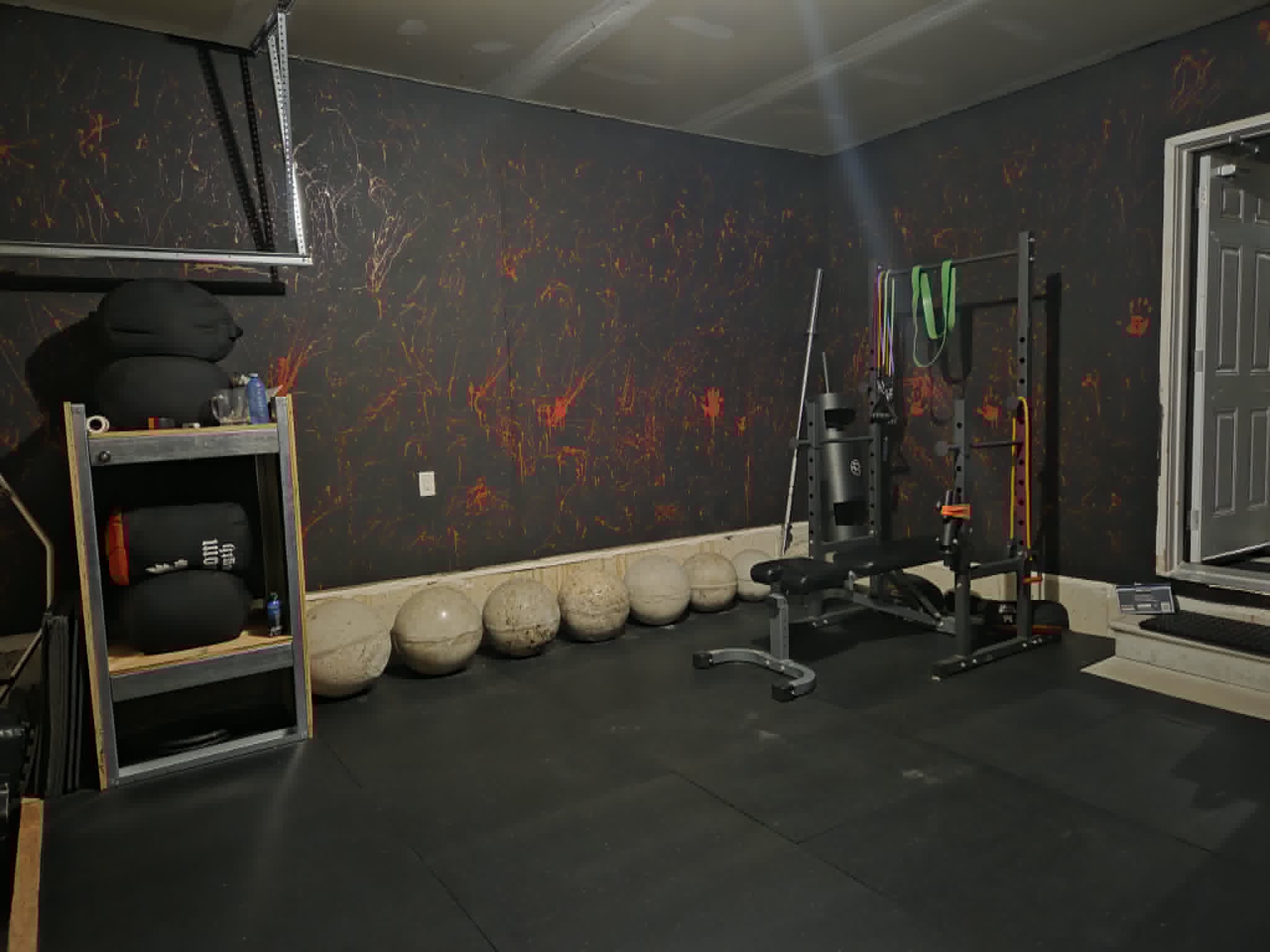 Atlas stones lined along the wall beside the squat rack and bench at SWALLFitness